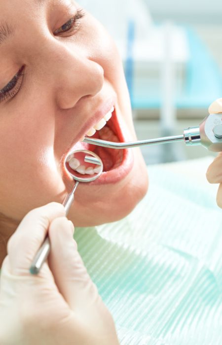 Girl sitting at dental chair with open mouth during oral check up while doctor. Visiting dentist office. Dentistry concept