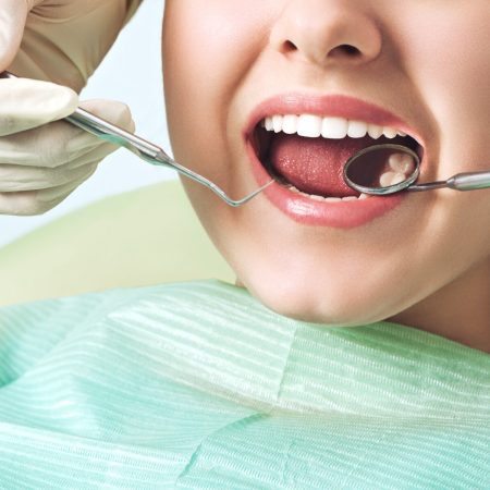 Girl sitting at dental chair with open mouth during oral check up while doctor. Visiting dentist office. Dentistry concept