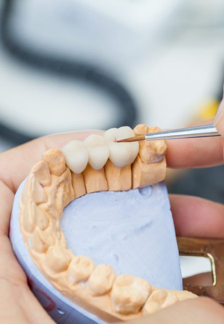 dental technician works by brush with jaw model