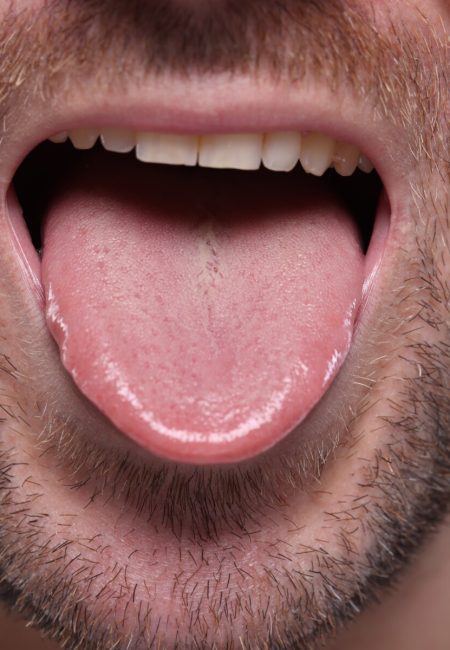 Closeup view of man showing his tongue on grey background