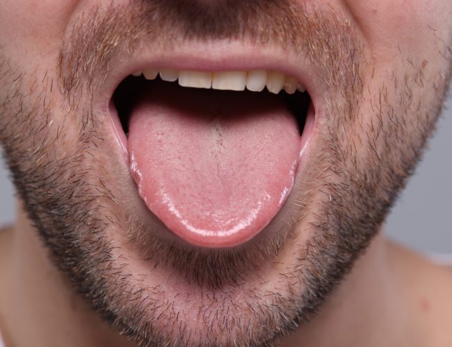 Closeup view of man showing his tongue on grey background