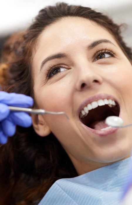 Head and shoulders portrait of beautiful young woman lying in dental chair with mouth open during consultation, copy space