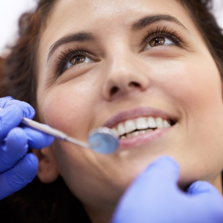 Closeup portrait of beautiful young woman lying in dental chair and smiling during consultation, copy space