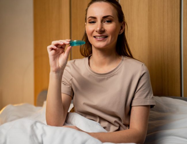 An attractive woman uses a multifunctional trainer at night, before going to bed. They help to align the growing teeth and correct the bite. Corrects the position of the tongue.